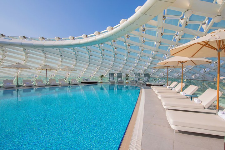 Sunbeds beside the turquoise Wet Deck pool beneath the white gridshell